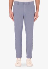 Pantaloni azzurri chiari con vestibilità slim, chiusura con zip e bottone. Realizzati in un tessuto morbido, con una sottile texture. Abbinati a sneaker bianche.
