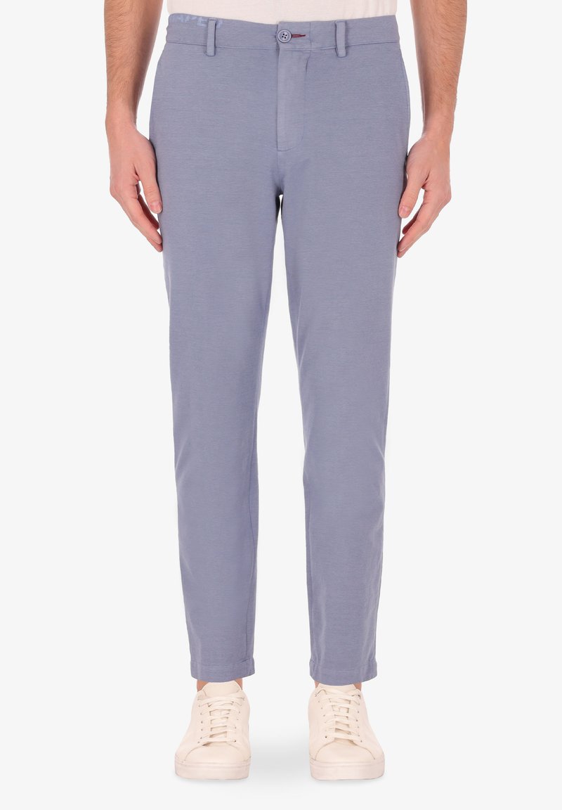 Pantaloni azzurri chiari con vestibilità slim, chiusura con zip e bottone. Realizzati in un tessuto morbido, con una sottile texture. Abbinati a sneaker bianche.