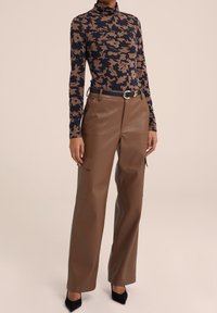 Hnědé široké kalhoty z umělé kůže s bočními kapsami, doplněné o přiléhavý rolák v námořnické modré a hnědé květinové vzory. Černý opasek s detailním sponou.
