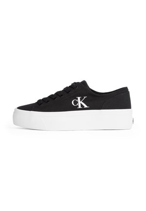 Sort lavt sneakers med tyk hvid sål og "cK" logo på siden, med sorte snørebånd og lærredsmateriale.