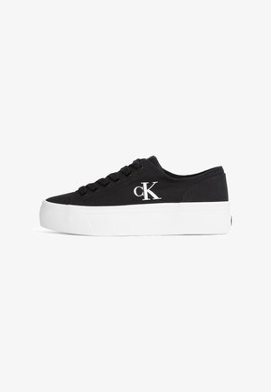 Czarny niski sneaker z grubą białą podeszwą i logo "cK" po boku, z czarnymi sznurowadłami i materiałem z płótna.