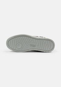 Weiße Sneaker-Sohle mit strukturiertem Muster und rutschfester Oberfläche, mit einem kreisförmigen Emblem und in Schwarz geprägtem "FILA"-Branding.