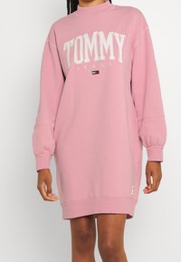 Rosa sweatshirtklänning i bomullsblandning. Funktioner stort vitt "TOMMY JEANS"-logotyp, ribbade ärmslut och en rak silhuett.