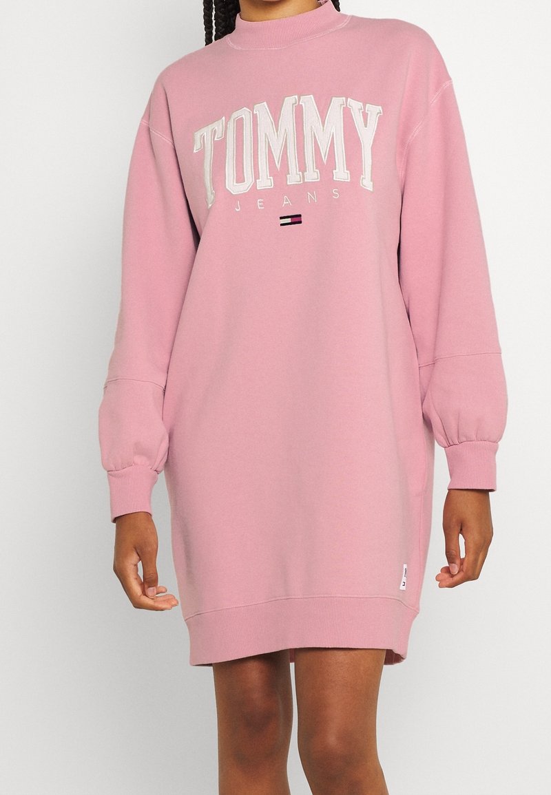 Rosa sweatshirtklänning i bomullsblandning. Funktioner stort vitt "TOMMY JEANS"-logotyp, ribbade ärmslut och en rak silhuett.