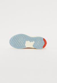 Suela de zapato con una base de goma azul texturizada, con acentos blancos y una pequeña sección roja en el talón, diseñada para ofrecer tracción y flexibilidad.