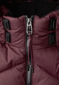 Burgunderfarbene Pufferjacke mit einem silbernen Reißverschluss, schwarzen Hardware-Details und einem weichen schwarzen Innenfutter mit gestepptem Design.