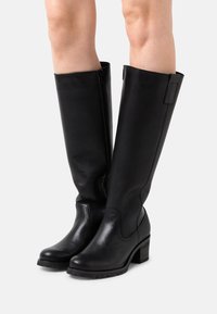 Czarne skórzane kozaki sięgające kolan o gładkim wykończeniu, kwadratowym nosku, teksturowanym obcasie typu blok oraz bocznym zamkiem błyskawicznym dla łatwego zakładania.