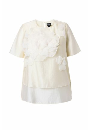 Kremowa bluzka z krótkim rękawem, z warstwowym dołem i dużymi, fakturowanymi aplikacjami kwiatowymi na przodzie i ramieniu.