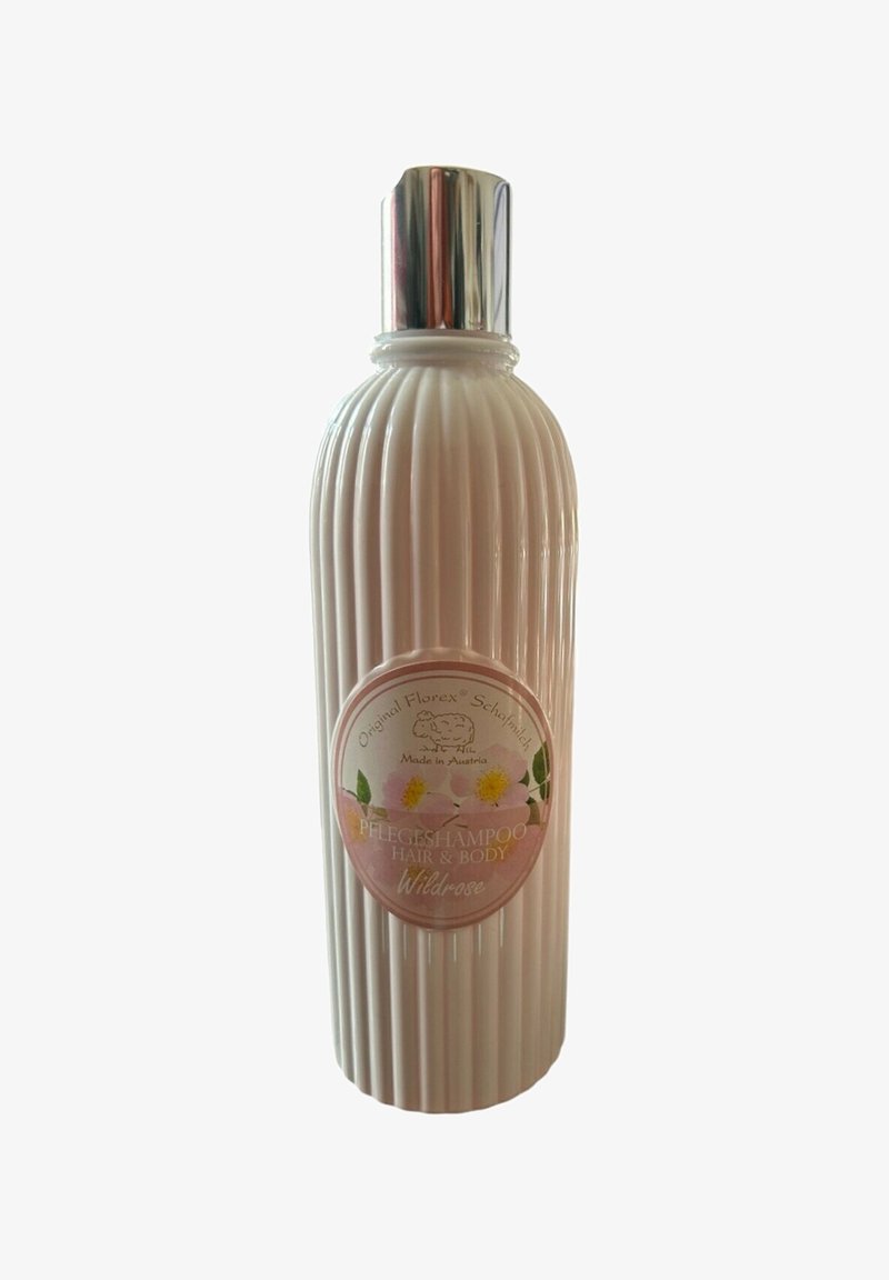 Pink ribbed shampoo and body wash bottle with a silver cap and floral label that reads "Wildrose." Made in Austria.