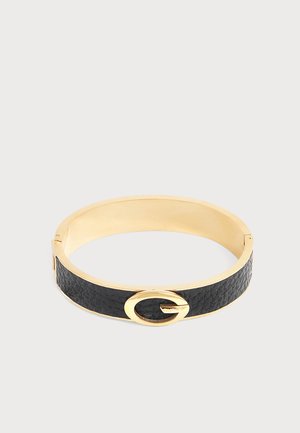 Bracelet jonc en or avec un bracelet en cuir noir texturé et un détail de boucle ovale dorée sur un fond clair.