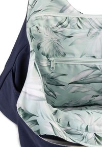 Marineblauwe stoffen tas met een lichtgroene binnenkant met een bladpatroon, inclusief een ritsvak en een zachte textuur.