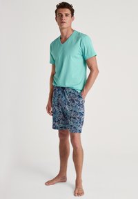 Turquoise v-hals t-shirt gecombineerd met gestreepte donkerblauwe shorts met blauwe en witte ontwerpen. Casual, ademend katoen.