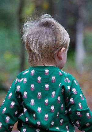 Grünes Langarmshirt mit einem sich wiederholenden Eulenmuster in Lila und Weiß. Weicher Stoff, runder Halsausschnitt und lockere Passform für hohen Tragekomfort.