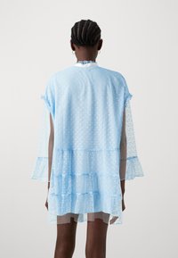 Ljusblå, lager-på-lager, genomskinlig klänning med volangärmar och hjärtmönster. Har rund halsringning och lös passform, lämplig för lager-på-lager.