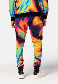Farverige sweatpants med et sprudlende mønster i levende nuancer af pink, blå, gul og grøn, med sorte ankleribkanter og en glat tekstur.