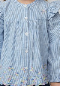 Gestreiftes Hemd in Blau und Weiß mit rundem Ausschnitt, Rüschensäumen, durchgehender Knopfleiste und floralem Stickerei am Saum in Pink und Gelb.