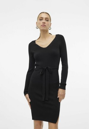 Robe tricot côtelée noire avec des manches longues, un décolleté en V, et une ceinture amovible à la taille, présentant des fentes latérales et une silhouette ajustée.