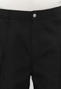 Black cargo pants with a textured finish, featuring a front button closure and side pockets, designed for functionality and comfort.