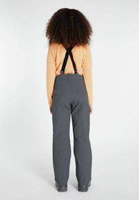 Grijze skibroek met verstelbare zwarte bretels, gecombineerd met een oranje T-shirt met lange mouwen. Bevat achterzakken en heeft een relaxte pasvorm.