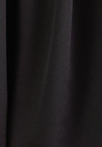 Tissu noir à texture lisse drapé en plis doux, montrant des détails fins de tissage et de subtiles réflexions de lumière.