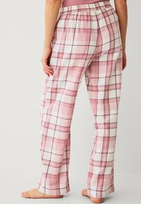 Roze en witte geruite pyjamabroek met een elastische tailleband, met losse pijpen en een zachte stofstructuur.