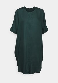 Abito camicia oversize di colore verde scuro, realizzato in stoffa liscia, con scollatura rotonda e maniche corte arrotolate; presenta una patta frontale.