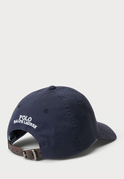 Jūras spēku kokvilnas beisbola cepure ar regulējamu brūnu ādas siksnu aizmugurē. Īpašs iezīme - izšūts "Polo Ralph Lauren" logotips baltā krāsā.