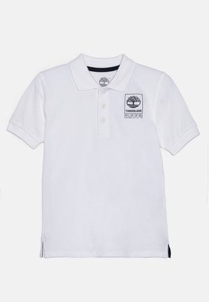 Maglietta polo bianca in cotone con colletto, apertura con tre bottoni e una patch nera con il logo Timberland sul petto. Fessure laterali all'orlo.
