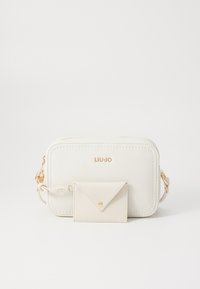 Weiße Leder-Crossbody-Tasche mit goldenen Beschlägen, abgerundeten Kanten, geprägtem Logo und einem passenden Umschlag-Kartenetui, das angebracht ist.