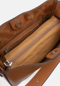 Borsa a tracolla in pelle marrone con fodera in tessuto, dotata di una tasca con cerniera e chiusura magnetica. Texture liscia con dettagli di cucitura ben evidenti.