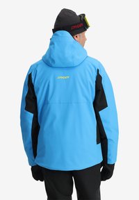 Giacca isolante blu e nera con cappuccio, polsini regolabili e logo Spyder. Tessuto morbido, progettata per attività all'aperto.