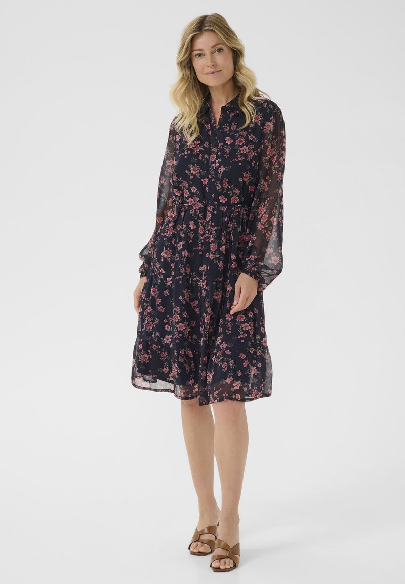 Dark floral dress with long, sheer sleeves and a tiered skirt, featuring pink flowers on a navy background. Includes a cinched waist.