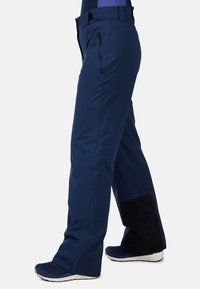 Marina utomhusbyxor med ett vattenavvisande tyg, rak bendesign, dragkedjefickor och en kontrasterande svart panel vid underbenet.