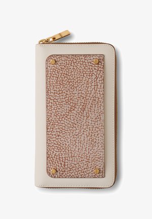 Beige Geldbörse mit Reißverschluss, die auf der Vorderseite mit einem strukturierten braunen Lederpatch gesichert ist, der von vier goldenen Schrauben gehalten wird. Der goldene Reißverschluss-Zipper ist oben links sichtbar.