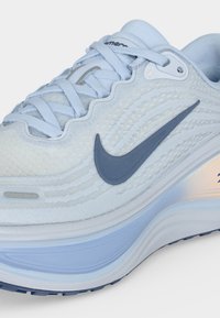 Ανοιχτό μπλε αθλητικό παπούτσι Nike με σκούρο μπλε λογότυπο Swoosh, υφασμάτινο επάνω μέρος, μαλακή σόλα και κλείσιμο με κορδόνια.