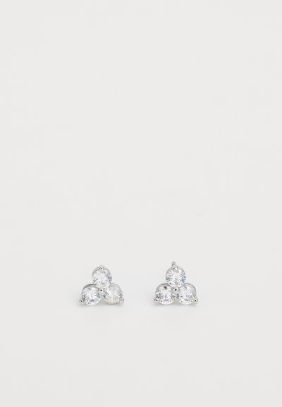 Des boucles d'oreilles à clou en argent présentent trois pierres claires en forme de poire disposées en un motif triangulaire, reflétant la lumière avec une finition étincelante.