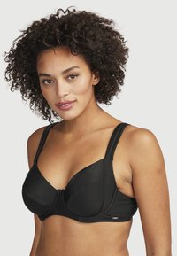 Svart bygellösa bh med släta kupor, breda axelband och subtila detaljer i metall. Mjuk tyg med strukturerad yta, designad för stöd.