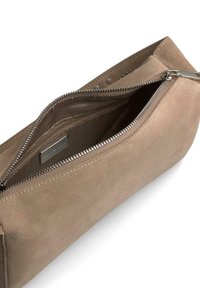 Prostokątna, beżowa torba z zamszu z metalowym suwakiem. Wnętrze wyłożone podszewką z małą kieszonką i widoczną metką marki wewnątrz.