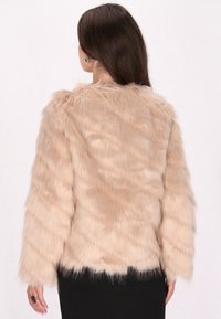 Chaqueta de piel sintética de color rosa claro con mangas largas, textura suave y un dobladillo ligeramente recortado, que presenta un escote redondo y sin cierres visibles.