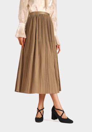 Gonna midi plissettata color marrone chiaro con una texture morbida, abbinata a scarpe con tacco blocco nere con listini incrociati.