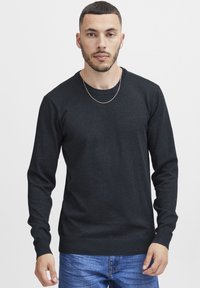 Mörkgrå, långärmad tröja i mjuk stickad tyg med rundad halsringning och ribbade ärmslut, ihopparad med jeans.