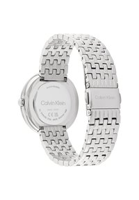 Montre en acier inoxydable argenté avec un bracelet maillon, un boîtier rond et un logo Calvin Klein gravé au dos et sur le fermoir. Résistante à l'eau.