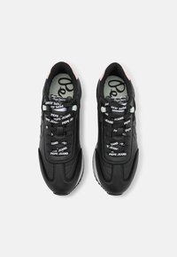 Black leather sneakers with textured detailing, white accents, and a logo on the tongue. Features multi-colored laces and a padded collar.