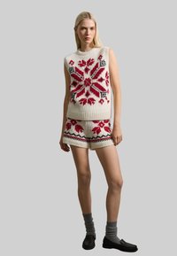 Strick ärmelloser Pullover und passende Shorts in Creme mit roten und schwarzen geometrischen Mustern. Textiles, elastisches Material. Zubehör nicht enthalten.