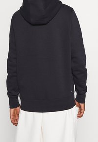 Navy Kapuzensweatshirt mit langen Ärmeln, gerippten Bündchen und Saum. Enthält ein kleines Markenlogo in der Nähe des Saums. Weicher Stoff.