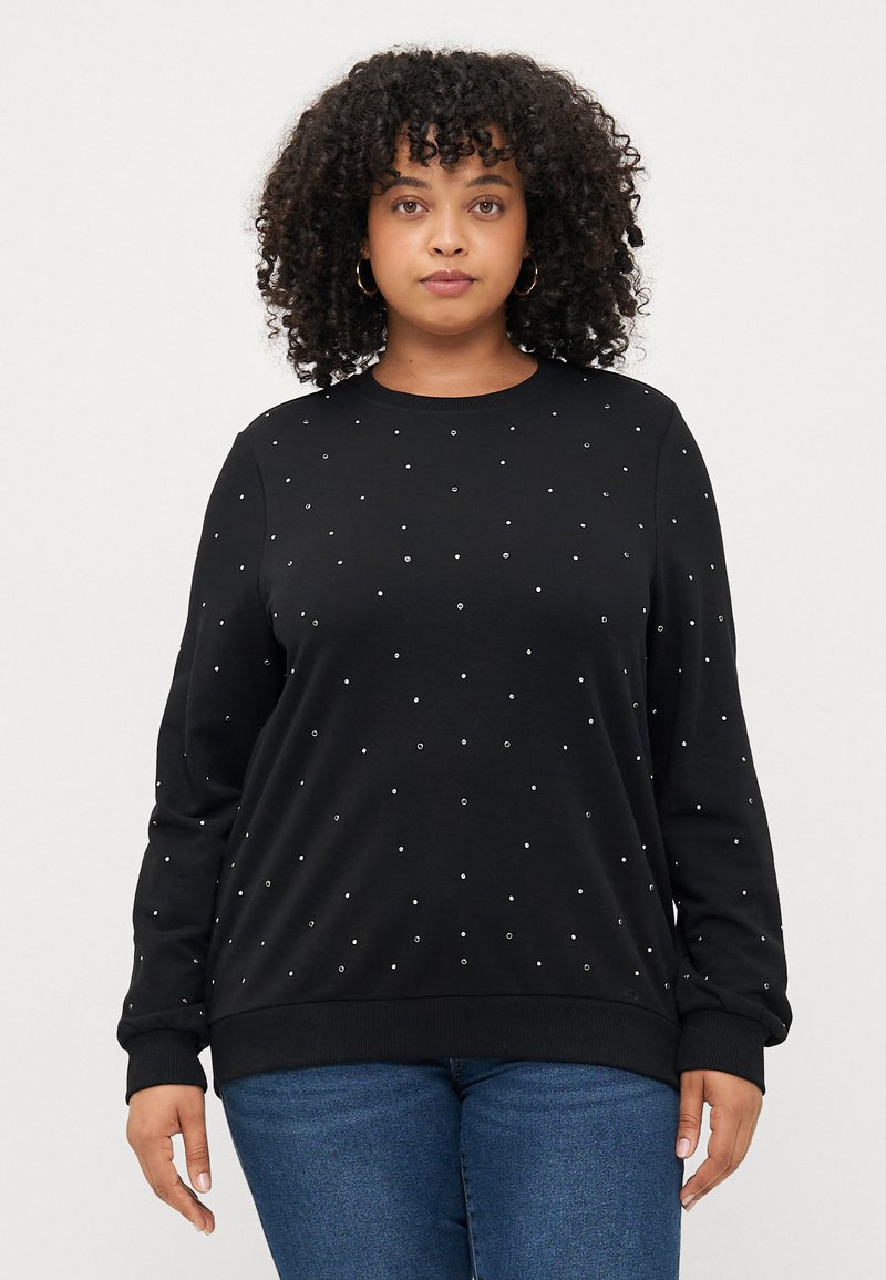 Sudadera negra de manga larga, con cuello redondo y decoraciones plateadas dispersas en la parte frontal. Tela suave, corte relajado y puños acanalados.