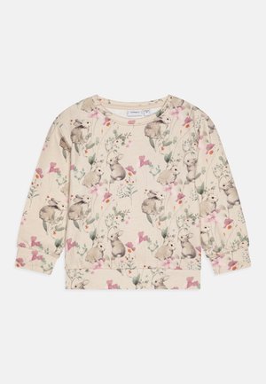 Beige sweatshirt med ett akvarellkanin- och blommönster, med långa ärmar och rundad halsringning. Mjuk tygtextur.