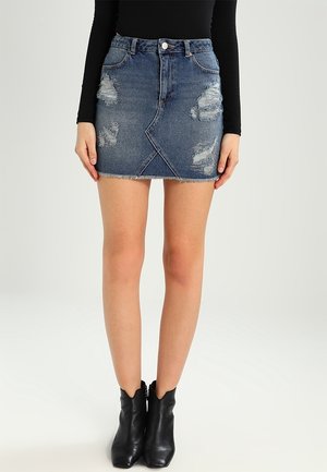Blå distressed denim mininederdel med forreste sømdetalje, båret med sorte ankelstøvler og en sort top med lange ærmer.