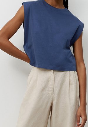 Niebieski krótki t-shirt z krótkimi opuszczanymi rękawami, wykonany z miękkiej bawełny. W połączeniu z lekkimi kremowymi spodniami o szerokich nogawkach, z fakturowanym wykończeniem.
