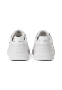 Baltie ādas tenisa apaviem ir gluda tekstūra, mīksts aizmugure un niansēti izšuvumi. Zīmols ir iepresēts uz papēža.